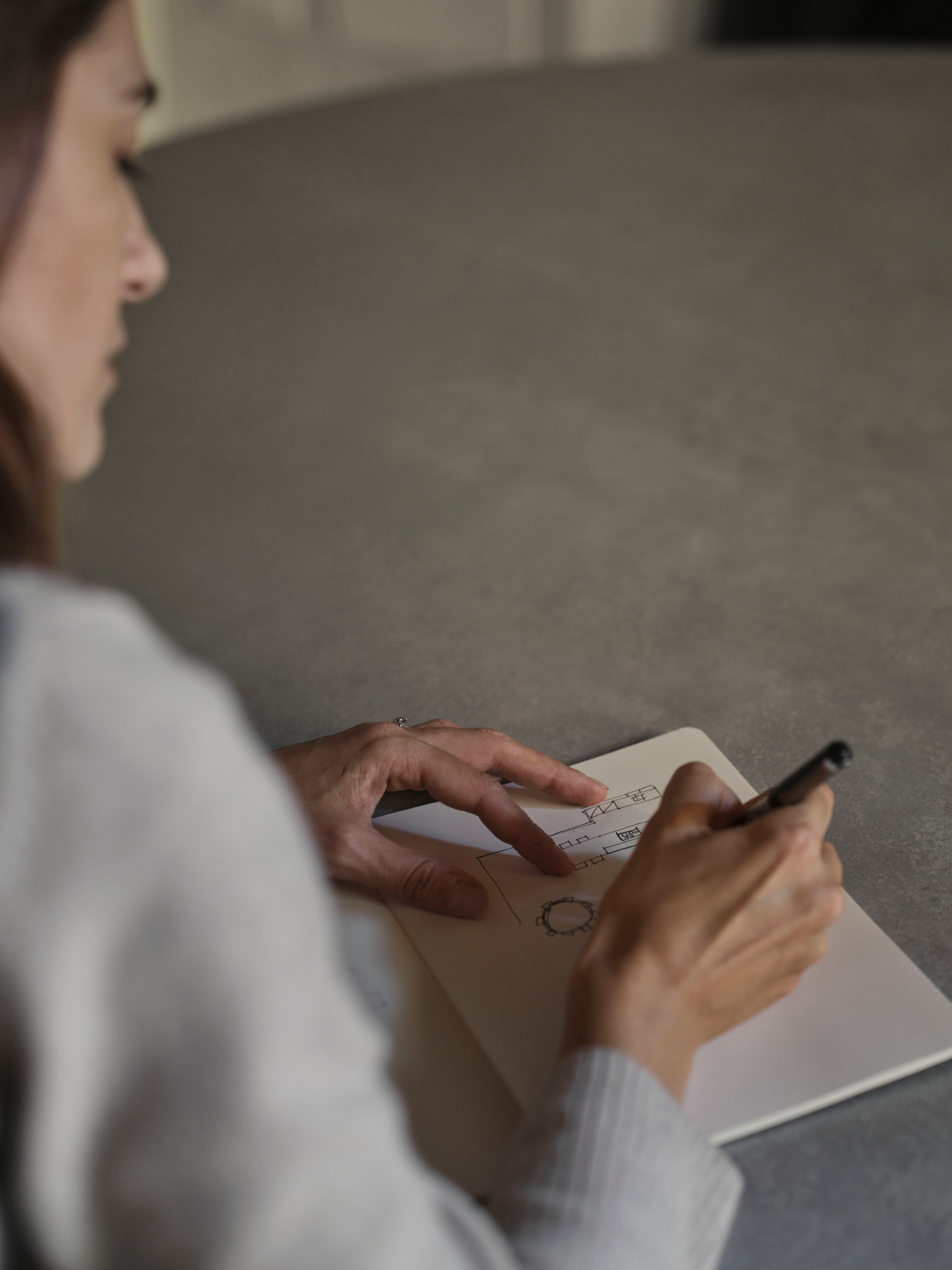 Francesca oggioni sitting at a desk while sketching in a notebook.